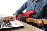 Female hipster music college student practicing electric guitar exercise, reading notes, pc laptop computer. Woman teaching herself, taking musical online courses. Background, close up